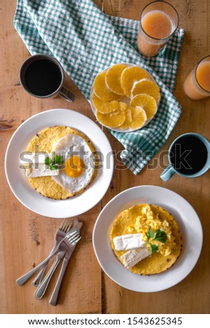 Breakfast flatlay of corn arepas with eggs, fresh fruit, coffee and juice