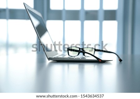 Workplace with notebook laptop on work table with office windows as background. Copy space