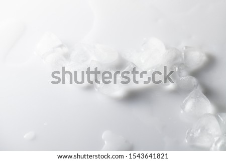 Background image of melting ice with water streaks on a white glossy background. The concept of preserving the beauty of the skin with ice