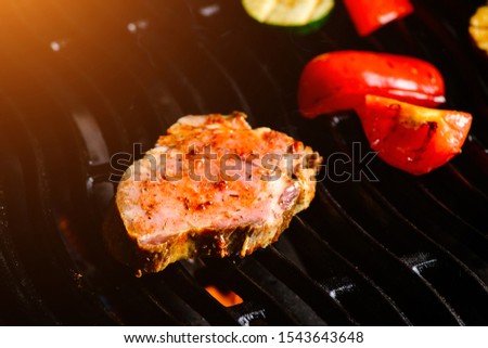 Beef steaks with vegetables on grill barbecue fire. grilled raw steak. Concept of flying food.