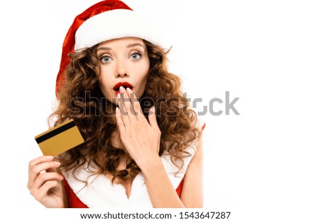 shocked woman in santa costume and hat holding credit card, isolated on white