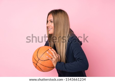 Young blonde woman over isolated pink background with ball of basketball