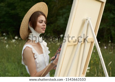 young woman in the fresh air with paints model girl paints on canvas