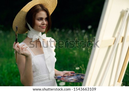young woman in the fresh air with paints model girl paints on canvas