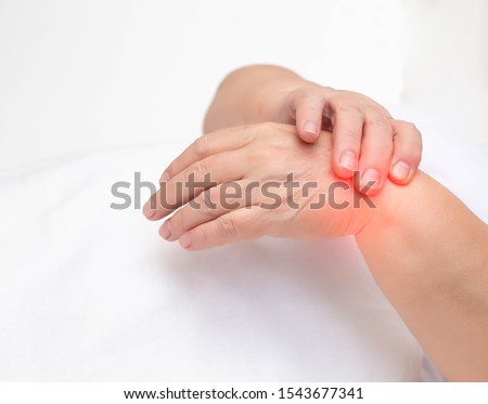 Woman holds on wrist joint on a white background. The concept of pain and inflammation of the wrist joint, tunnel syndrome and arthritis, copy space Royalty-Free Stock Photo #1543677341