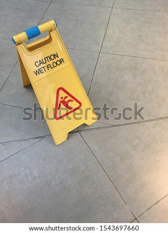 A yellow caution wet floor sign placed on tiled floor.