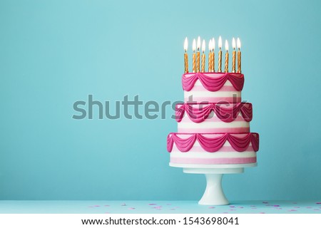 Pink tiered birthday cake with birthday candles Royalty-Free Stock Photo #1543698041