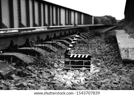 Black clapperboard with train tracks on background. Directing and filming cinema movie. Travel story.