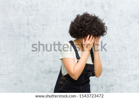 young pretty afro woman covering eyes with hands with a sad, frustrated look of despair, crying, side view