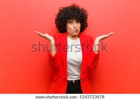 young pretty afro woman feeling puzzled and confused, doubting, weighting or choosing different options with funny expression