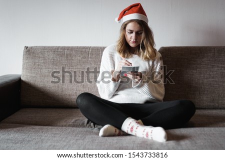 Portrait of pretty girl on the sofa at Christmas writes plans for the new year