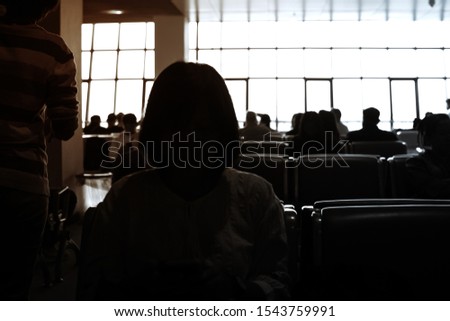 Blurred photography of woman sitting sitting on the bench in modern airport at the passenger zone for waiting airline call.