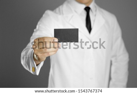 Doctor. A man in a white coat, white shirt and black tie holds a black business card. Without a face.