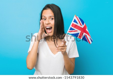 Young hispanic woman holding a united kingdom flag shouting excited to front.