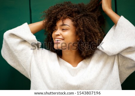 Close up portrait of laughing young african american with hands in hair looking away