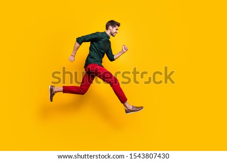 Full size profile side photo of positive cheerful guy jump run fast want hurry to sales discounts wear casual style clothes sneakers isolated over yellow color background