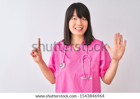 Young beautiful Chinese nurse woman wearing stethoscope over isolated white background showing and pointing up with fingers number six while smiling confident and happy.