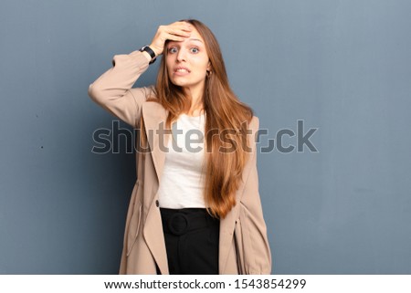 young pretty woman panicking over a forgotten deadline, feeling stressed, having to cover up a mess or mistake against gray background Royalty-Free Stock Photo #1543854299