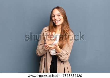 young pretty woman feeling happy and successful, smiling and clapping hands, saying congratulations with an applause against gray background Royalty-Free Stock Photo #1543854320