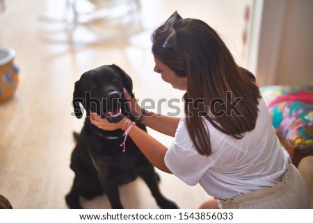 Young beautiful woman at home playing with black labrador dog