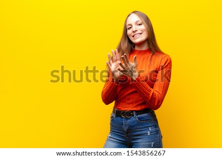 young pretty woman feeling happy and successful, smiling and clapping hands, saying congratulations with an applause against orange background Royalty-Free Stock Photo #1543856267