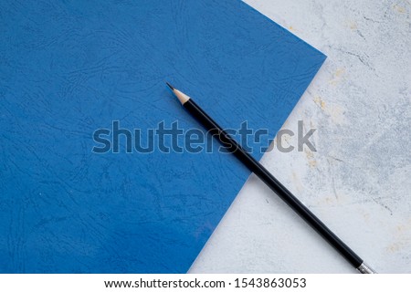 white desktop, green notebook lies on the table, pensil, with copy space, for advertisement, top view