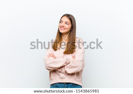 young pretty woman feeling happy, proud and hopeful, wondering or thinking, looking up to copy space with crossed arms against white background Royalty-Free Stock Photo #1543865981