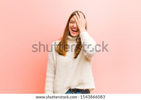 young pretty woman laughing and slapping forehead like saying d‚Äôoh! I forgot or that was a stupid mistake against pink background Royalty-Free Stock Photo #1543866083