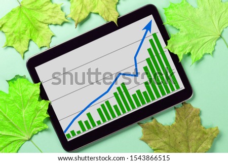 A tablet with a business graph on the desktop. Autumn leaves background