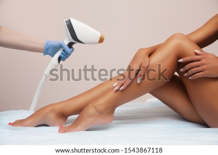 Laser epilation and cosmetology in beauty salon. Hair removal procedure. Laser epilation, cosmetology, spa, and hair removal concept. Beautiful woman getting hair removing on legs Royalty-Free Stock Photo #1543867118