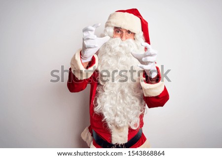 Middle age handsome man wearing Santa costume standing over isolated white background Shouting frustrated with rage, hands trying to strangle, yelling mad