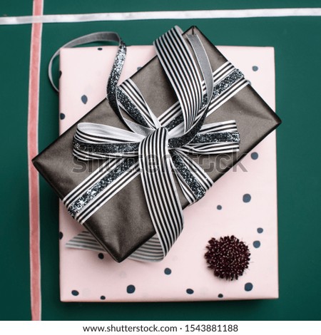 Gift box wrapped in paper with ribbon, wrapping materials, and scabiosa on a green background