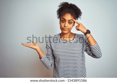 African american woman wearing navy striped t-shirt standing over isolated white background confused and annoyed with open palm showing copy space and pointing finger to forehead. Think about it.