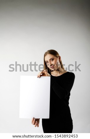 Young attractive woman in black is holding white paper.