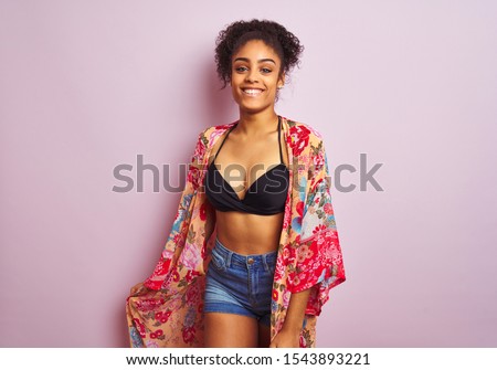 Young beautiful african american woman on vacation standing wearing bikini and colorful caftan