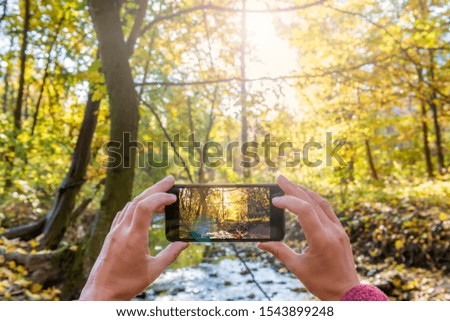 Smartphone camera in hands taking photo of a beautiful morning landscape. First-person view.
