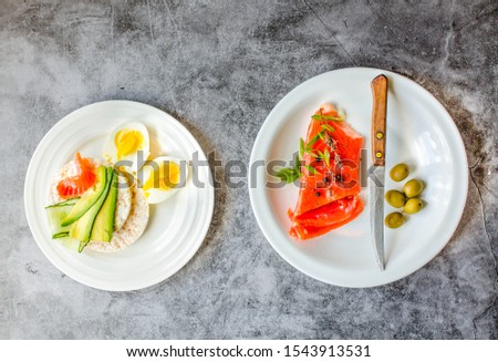 Rice crispy cakes with avocado and fresh salted salmon fillet with eggs on a gray marble background. Top view. Space for text. High protein and low carb meal.