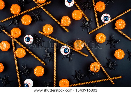 Halloween background with many pumpkin, candy eyes and spiders on black, autumn holidays concept, harvesting, copy space, top view, mockup