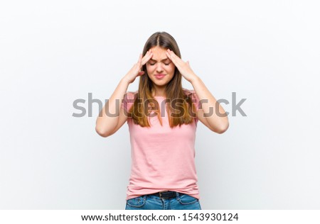 young pretty woman looking stressed and frustrated, working under pressure with a headache and troubled with problems against white background Royalty-Free Stock Photo #1543930124
