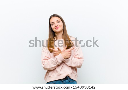young pretty woman looking puzzled and confused, insecure and pointing in opposite directions with doubts against white background Royalty-Free Stock Photo #1543930142