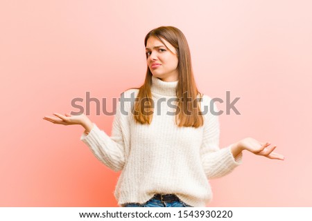 young pretty woman looking puzzled, confused and stressed, wondering between different options, feeling uncertain against pink background Royalty-Free Stock Photo #1543930220
