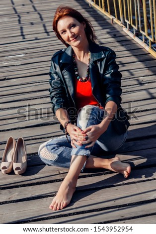 A girl walks on a wooden bridge. Portrait in a jacket. On a sunny day.