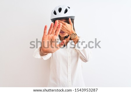 Beautiful businesswoman wearing glasses and bike helmet over isolated white background covering eyes with hands and doing stop gesture with sad and fear expression. Embarrassed and negative concept.