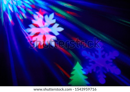 rays of light on a black background. Colored snowflakes and christmas trees