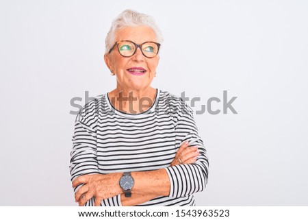 Senior grey-haired woman wearing striped navy t-shirt glasses over isolated white background smiling looking to the side and staring away thinking.