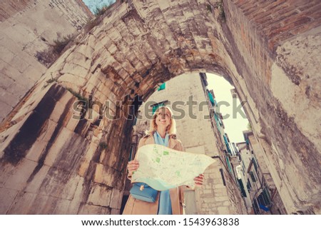 Travel and active lifestyle concept. Young traveller woman walking in ancient town holding tourist map.