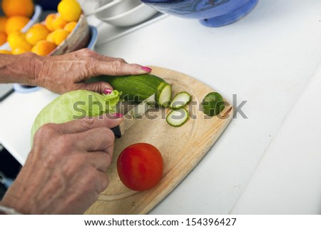 Cropped image of senior woman cutting vegetables on chopping board in kitchen