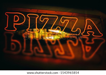 Red neon pizza sign reflected during night time. Warm neon light photo.
