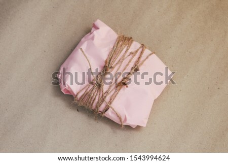 Soft pouch wrapped in craft paper and tie cord. Crumpled paper background texture. Delivery service. Online shopping.	
