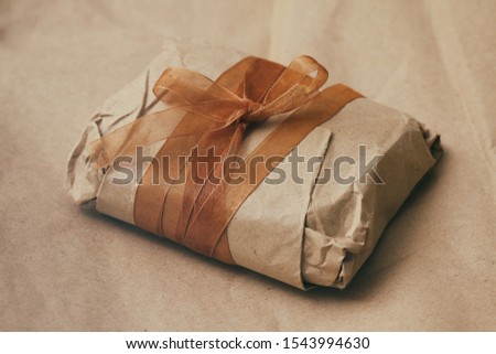 Soft pouch wrapped in craft paper and tie brown silk ribbon. Crumpled paper background texture. Delivery service. Online shopping.	
